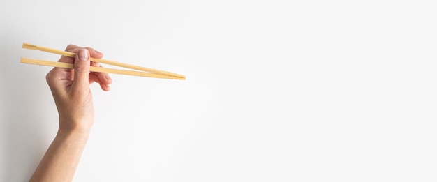 Woman's hand holding two chinese chopsticks on a white background Banner