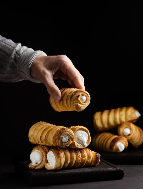 A woman's hand holds a baked tube with whipped protein cream black background