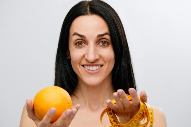 Woman's hand holds a centimeterlong ribbon and lemon fruit The concept of a healthy lifestyle natural organic food concept