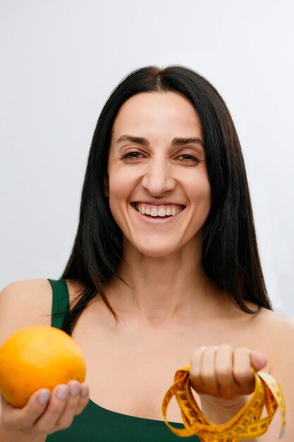 Woman's hand holds a centimeterlong ribbon and lemon fruit The concept of a healthy lifestyle natural organic food concept