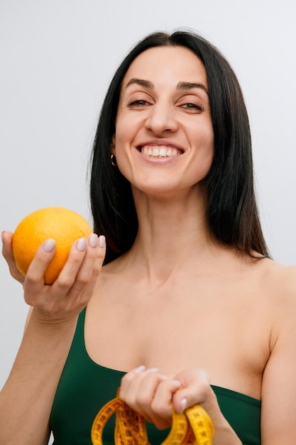 Woman's hand holds a centimeterlong ribbon and lemon fruit The concept of a healthy lifestyle natural organic food concept