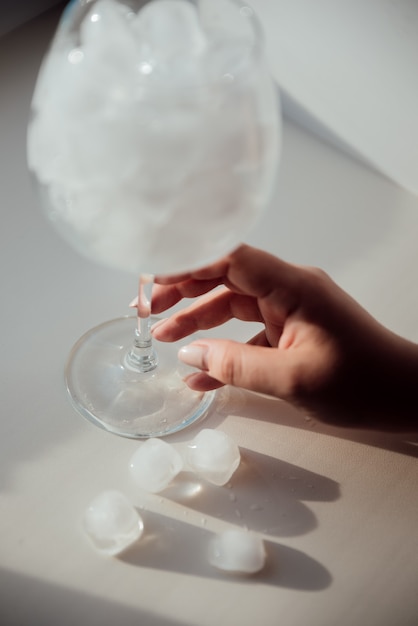 A woman's hand holds a glass with ice