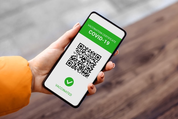 La mano di una donna tiene un telefono cellulare con un certificato internazionale covid 19 dell'applicazione in città