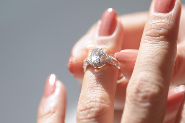 A woman's hand holds a ring with a diamond on it.