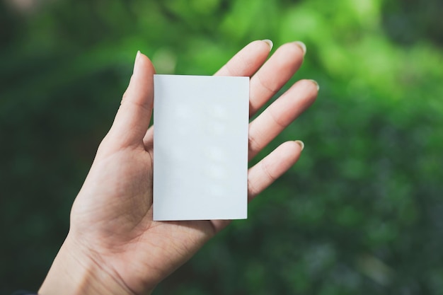 Foto la mano di una donna tiene un piccolo foglio bianco vuoto con spazio per il testo