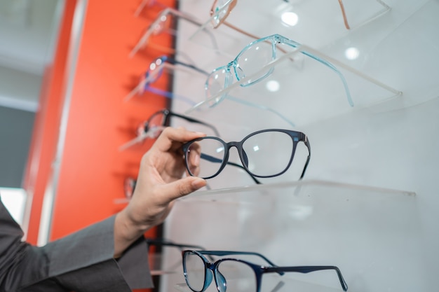 A woman's hand is holding a pair of glasses stuck to a window in the eye clinic