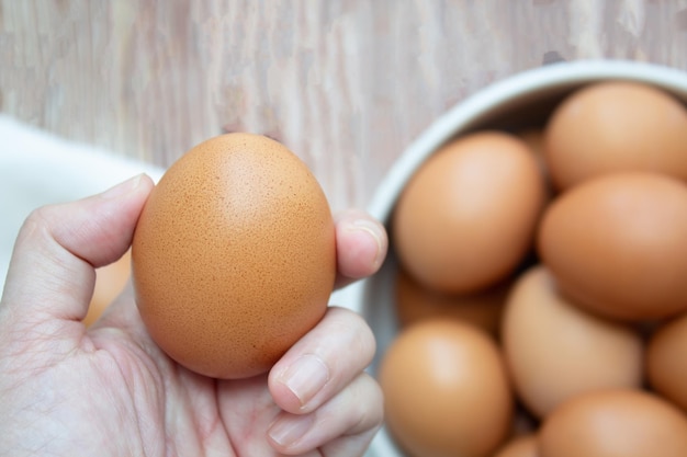 女性の手は卵のボウルを拾い上げ、それを持って食べ物を準備する