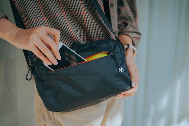 a woman's hand is putting a cell phone into a small bag