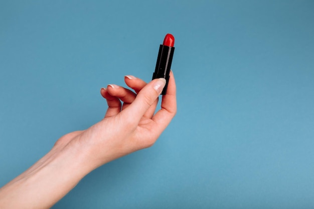 Photo the woman's hand is taking red lipstick isolated on the blue background