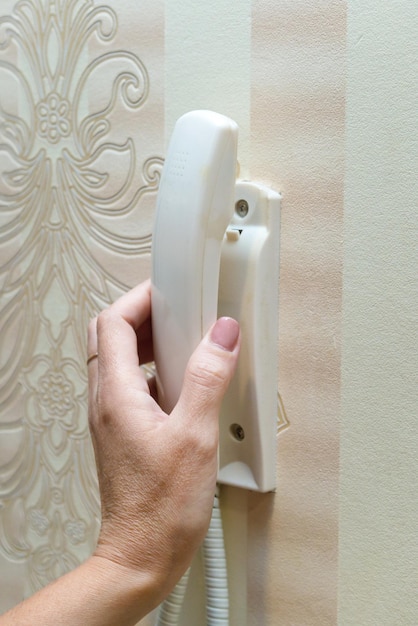 Photo a woman's hand lifts the white handle from the intercom inside the apartment