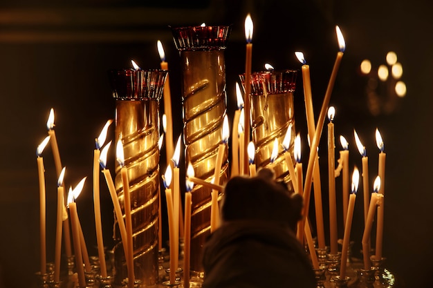 Woman's hand lights a candle in the dark church