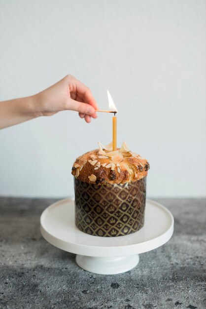 A woman's hand lights candles on an Easter cake