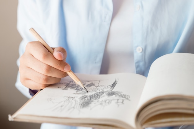 Photo a woman's hand makes a sketch in a notebook.