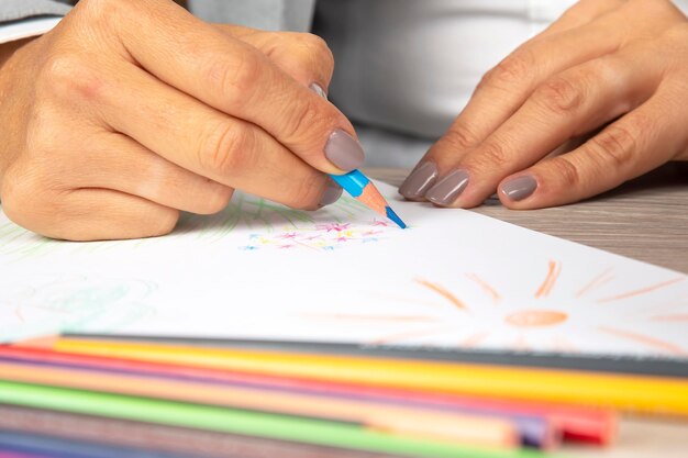 Woman's hand in the office draws with crayons on paper