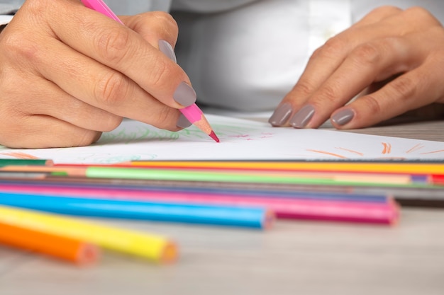 Woman's hand in the office draws with crayons on paper
