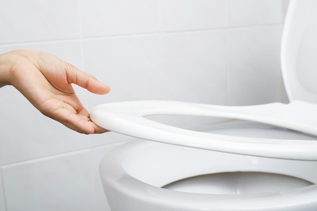 Woman's hand opening the toilet lid