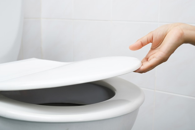 Woman's hand opening the toilet lid