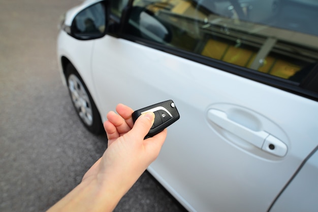 woman's hand operate remote key car for open lock door
