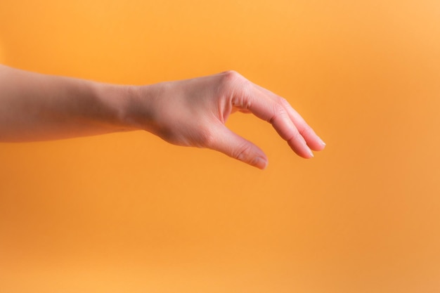 Mano della donna su uno sfondo arancione con il palmo della mano verso il basso