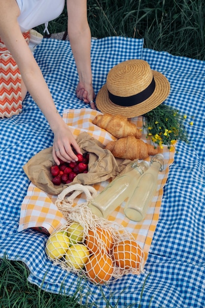 A woman's hand picks up a strawberry for a picnic in nature