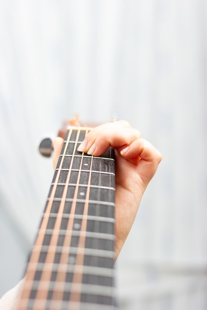 Женская рука играет на акустической гитаре