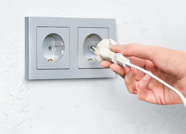 Woman's hand plugging a plug into an outlet