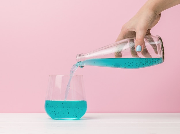 Photo a woman's hand pours a cocktail on a red surface