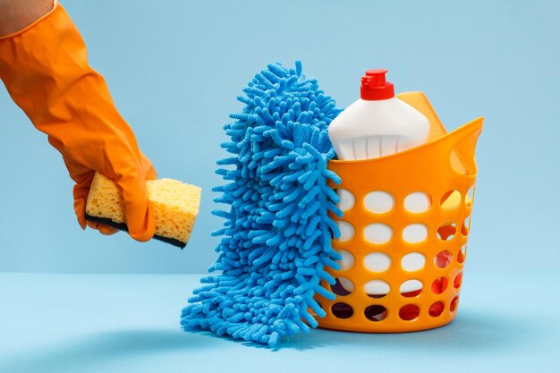 Woman's hand in protective glove with sponge on the blue background