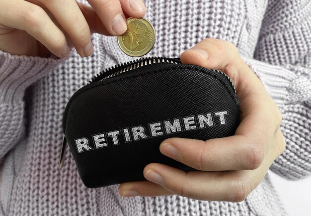 Foto mano della donna che mette moneta nel portafoglio nero con la parola pensionamento