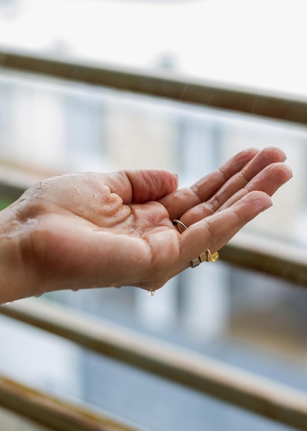 La mano della donna sotto la pioggia davanti alla finestraxa