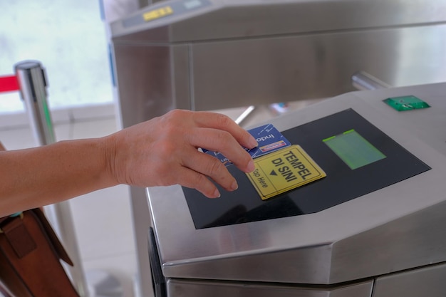 A woman's hand swipes an electronic money card to enter the station