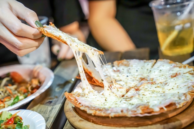 La mano della donna prende i pezzi di pizza dal piatto della pizza in un evento di foodtruck, la pizza di cheese è allungata da lei.
