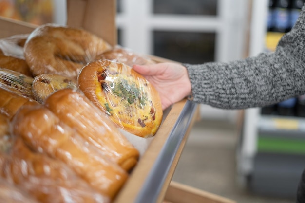 A woman's hand takes a small white flour pizza from a wooden shelf in a supermarket Baking for sale Copy space