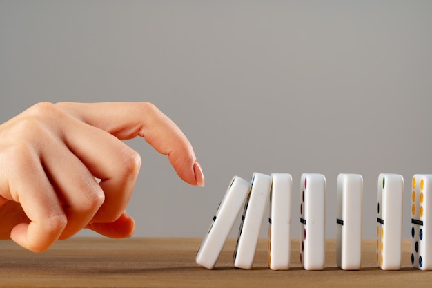 Mano di donna che fa cadere pezzi di domino