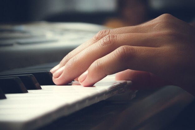 La mano di una donna tocca i tasti del pianoforte