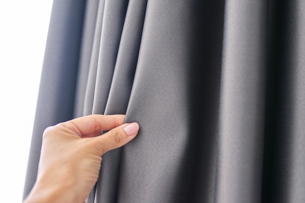 Woman's hand touching curtain gray blackout fabric lightblocking fabric