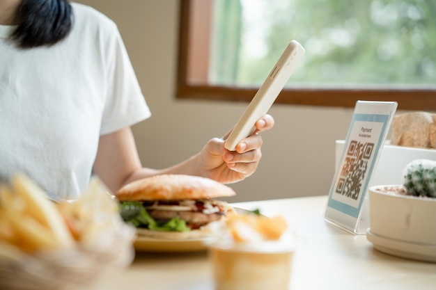 Woman's hand uses a phone to scan a qr code in a restaurant to receive a discount or pay for food Use phone to transfer money or pay online without cash