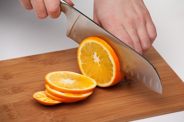 Фото Женская рука с ножом вырезать сочный апельсин