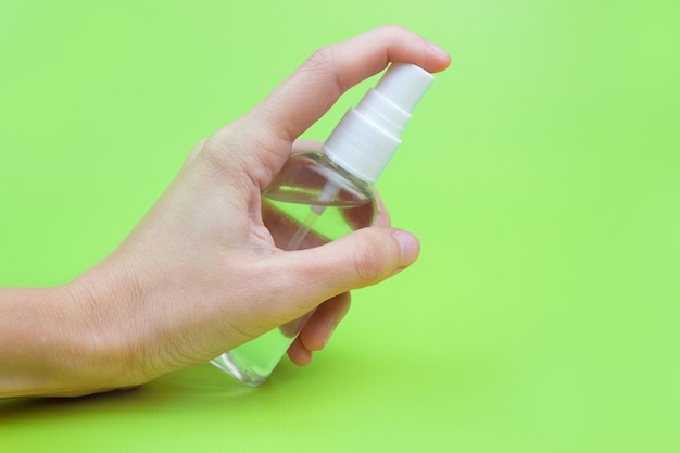 A woman's hand with an antiseptic on a green background close-up. The concept of hygiene and cleanliness. Disinfectant