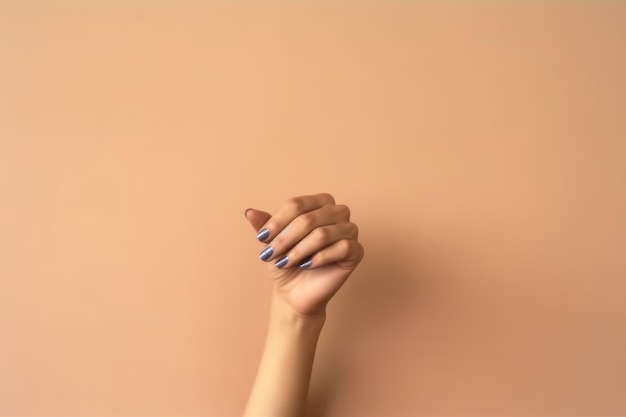 A woman's hand with blue nail polish on a peach background