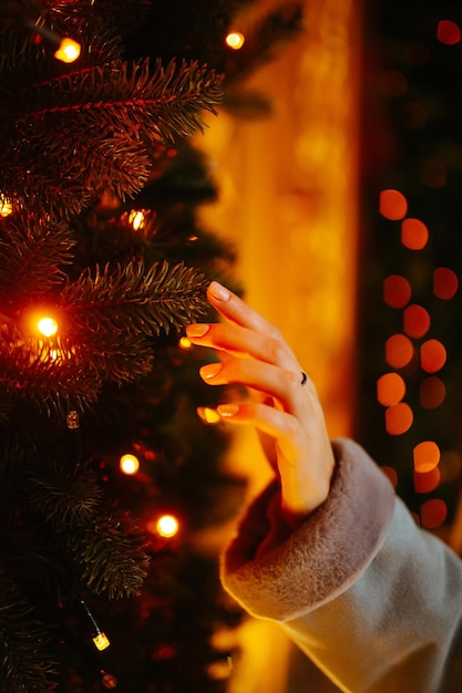 ツリーのクリスマス ライトと女性の手お祝いクリスマス フェア冬の休日の概念