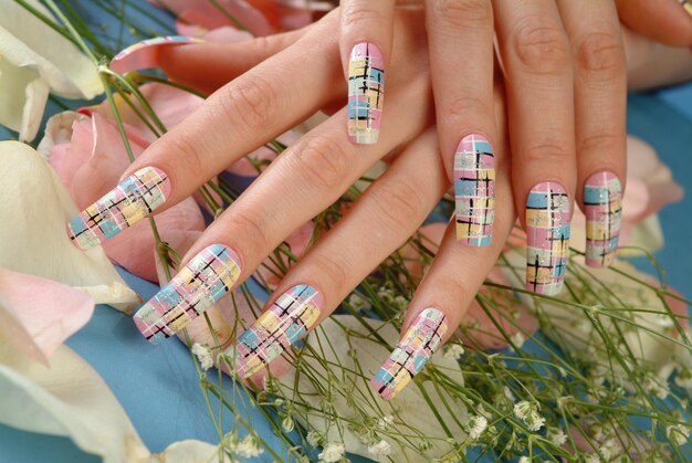 Женская рука с цветным лаком для ногтей на букете цветов