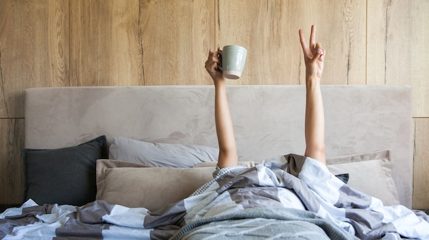침대에서 커피 한잔과 함께 여자의 손, 새로운 하루의 시작 개념, 좋은 아침