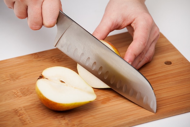 Foto la mano della donna con un coltello da cucina ha tagliato la pera