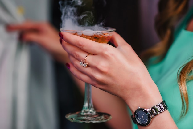 Woman's hand with a Martini glass with bubbles and steam