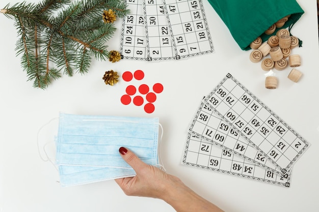 Woman's hand with mask and wooden barrels with cards for a game in lotto