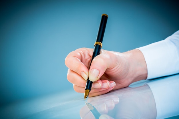 Woman's hand with a pen on a blue background