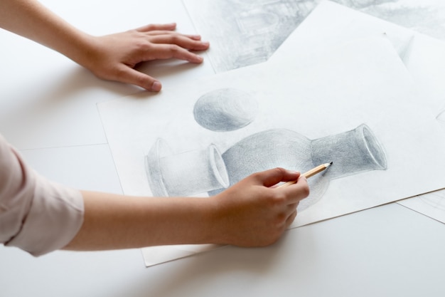 A woman's hand with a pencil. Draws a still life.