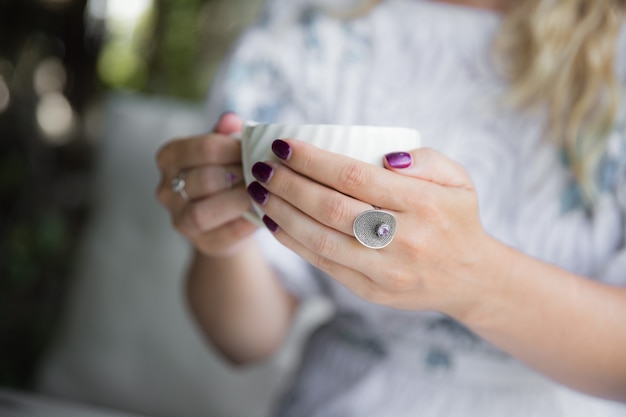 Woman's hand with ring holding cup of cappuccino