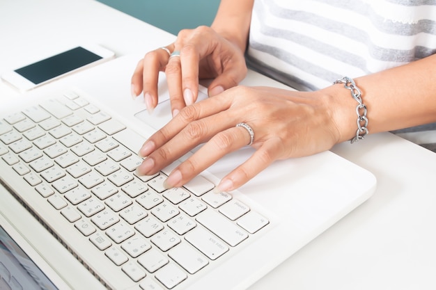 Woman's hand with wedding ring using laptop computer. Technology and lifestyle concept